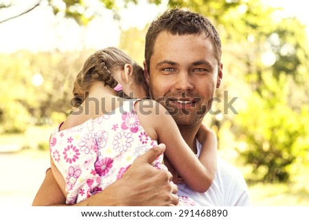 Handsome man holding a baby and looking at the camera smiling and feeling happy