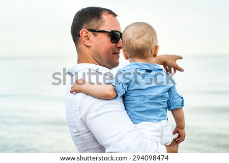 A man holds a child and shows him explaining away what is there