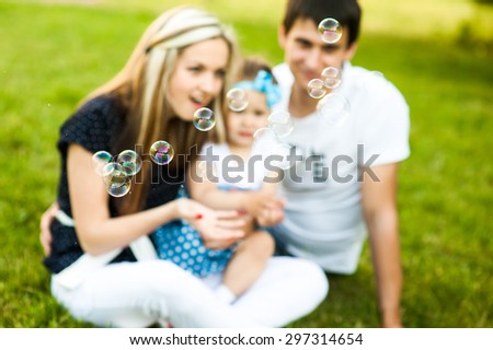 Family sitting together on the lawn and blow bubbles