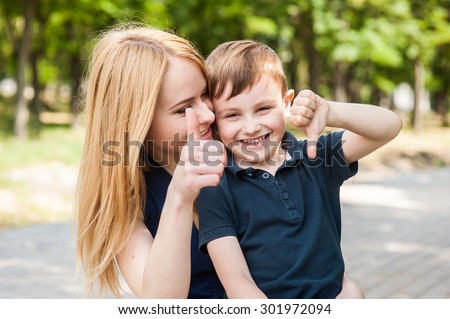 Mother and son together outdoors show thumb and say that everything is fine or not