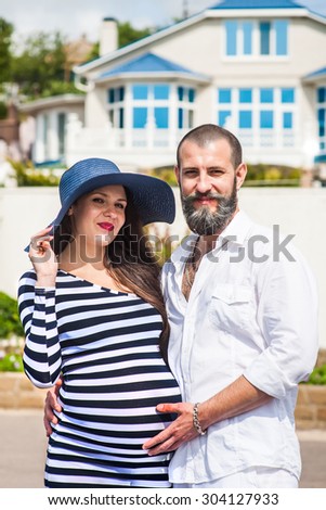Beautiful young pregnant woman with man near the house feel peace and tranquility