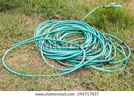 Green hose on the grass of small farm.
