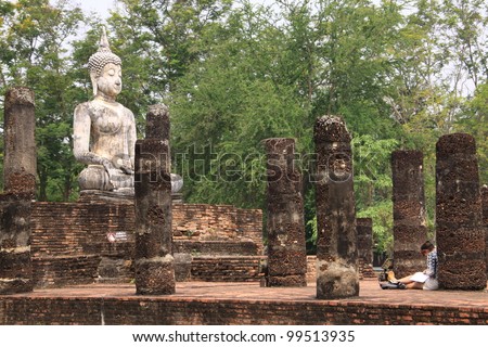 Traveler enjoy drawing picture of ancient buddha in Sukhothai historical park, Thailand