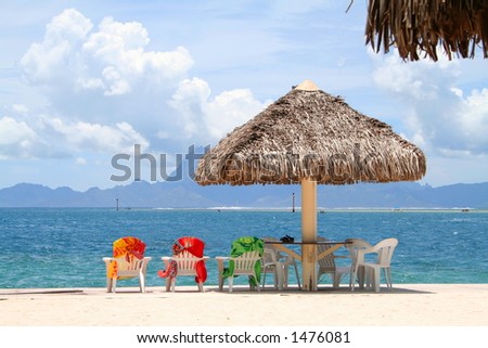 Three colorful chairs aligned on a beach in Tahiti, French Polynesia