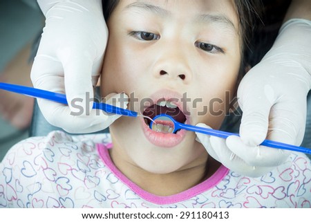 Close up little girl with Dentist examining a patient\'s teeth in the dentist