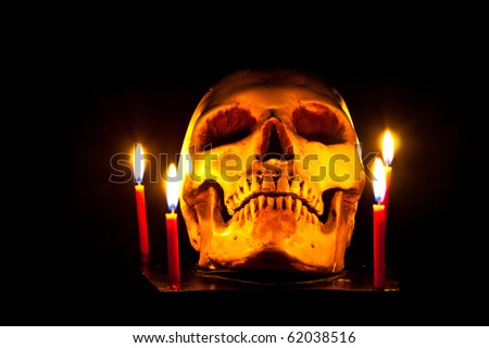 Halloween image with a burning candle and ancient skull