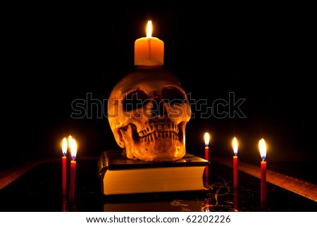 Halloween image with a burning candle and ancient skull on book