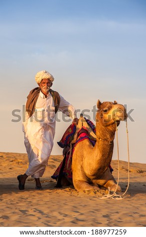 JAISALMER, INDIA - FEB 26: Cameleer and his herd at the Sam Sand Dune on  Feb 26, 2013 in Jaisalmer, India. Apart from farming, camel riding activity is  another income source for desert villagers