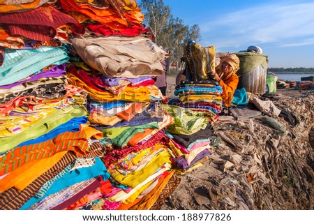 AGRA, INDIA - MAR 01: A woman arranges customers\' clothes on March 01, 2013 in Agra, India. Laundry is to be done on a riverbank in India.