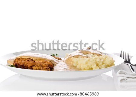 Chicken fried steak with mashed potato and gravy on a white plate.