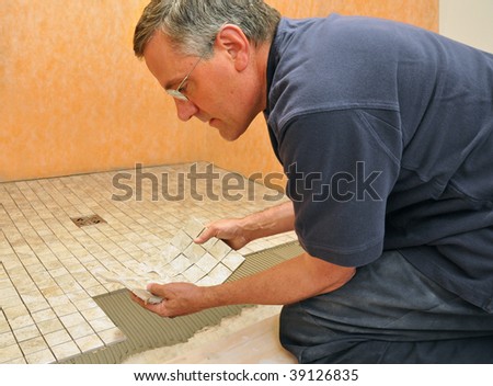 Man installing sheet of mosaic ceramic tiles on shower floor