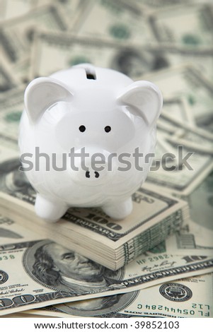 Close up of a cute Piggy Bank on a stack of cash. Shallow depth of field.