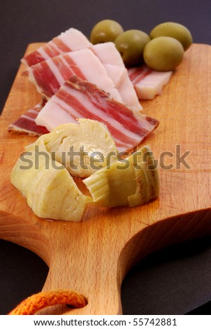 Close up of bacon, green olives, artichoke hearts with black background