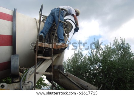 A worker performs routine maintenance cleaning a cement mixer truck Concrete