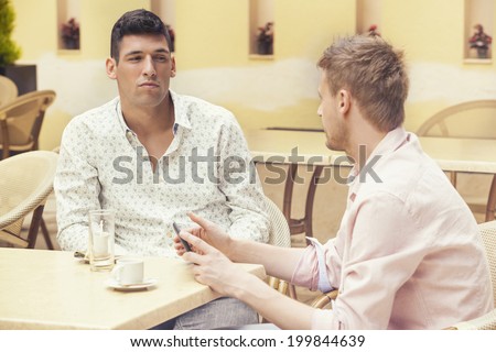 Two friends drinking coffee and talking in the cafe bar