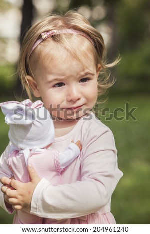 Cute little girl playing with a doll in the park