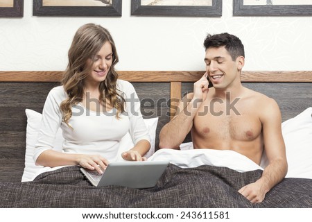 Attractive young woman working on the notebook, boyfriend talking on the phone