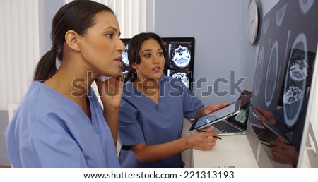 Black and hispanic female doctors working together with cell phone