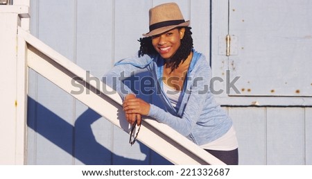 Black woman leaning on wooden rail smiling