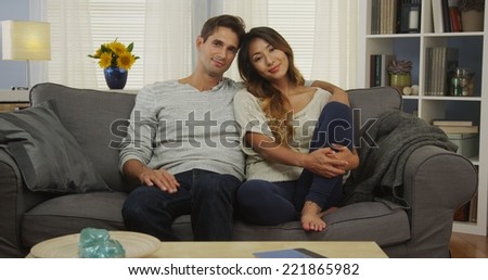 Mixed race couple sitting on couch smiling
