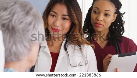 Japanese woman doctor and nurse talking to elderly patient in bed