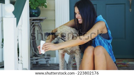 Mixed race woman sitting on porch taking pictures with dog