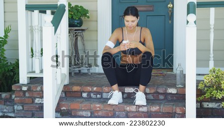 Hispanic woman starting playlist before going out for a run