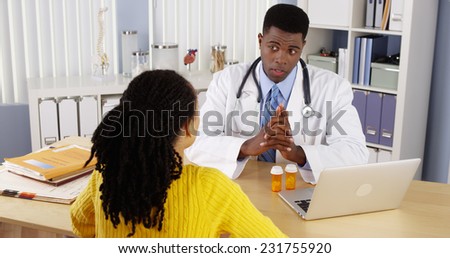 African American patient talking to African American doctor at office desk