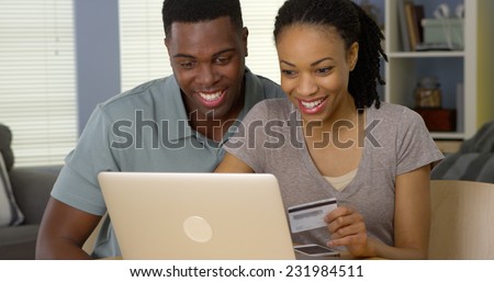 Smiling young black couple using credit card to make online purchases