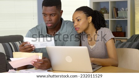 Serious young black couple paying bills online with laptop computer