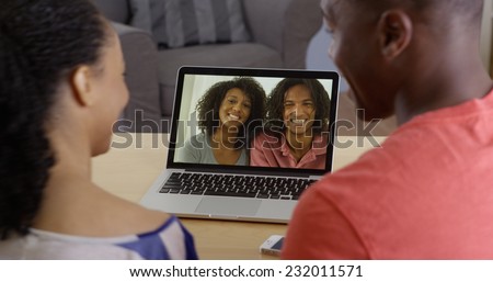 Young black couple having internet video chat with two friends on laptop