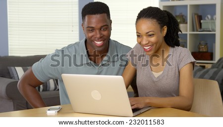 Young black man and woman using laptop together at desk