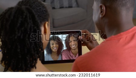 African American couple talking to friends over tablet computer video chat