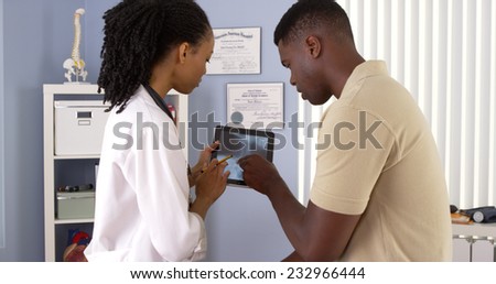 Black female doctor using tablet computer to share x ray with patient
