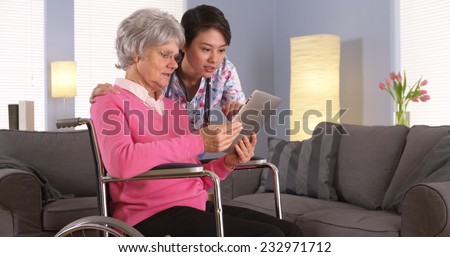 Elderly patient and Asian nurse talking with tablet
