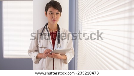 Asian woman doctor using tablet by window