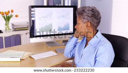 Senior black business woman talking on phone by computer