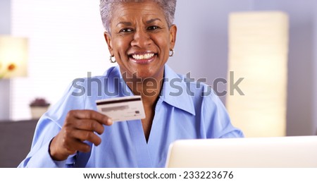 Happy Mature Black woman typing in card information