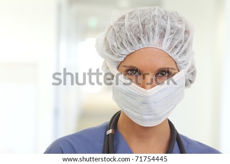Portrait of serious young woman doctor in scrubs with mask and cap