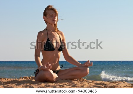 Silhouette of woman in yoga lotus meditation position back to seaside