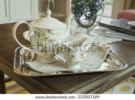 ceramic teapot and cups on a stainless steel tray in living room