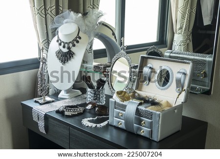 Beauty and make-up concept: table mirror,sunglasses,jewelry and makeup brushes on a black table