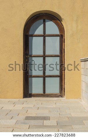 wood arched window with rough plaster wall