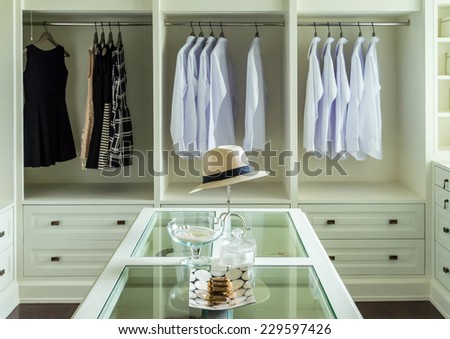 white hat and jewelry set on a dresser table in a walk in closet room.
