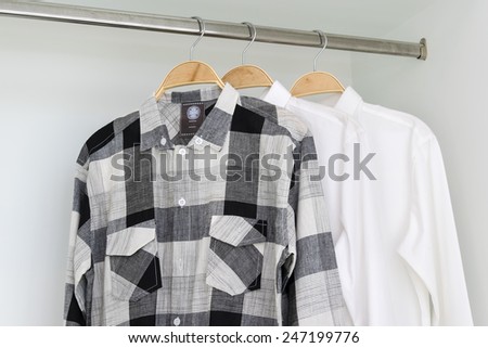 row of shirts hanging on coat hanger in white wardrobe