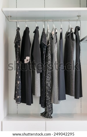 modern closet with row of black dress hanging on coat hanger in wardrobe.