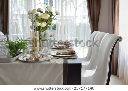 dining wooden table and comfortable chairs in modern home with elegant table setting