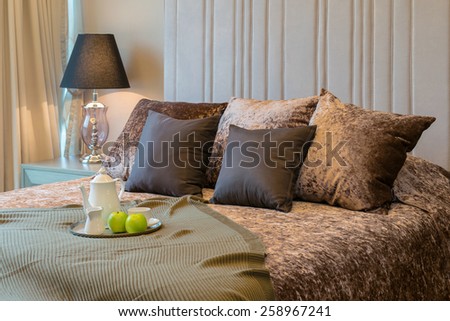 Decorative tray with tea set and green apple on the bed for breakfast.