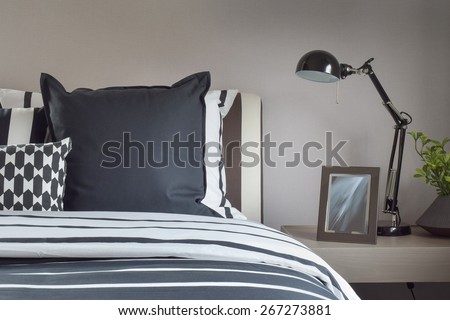 Modern bedroom interior with pillows and reading lamp on bedside table