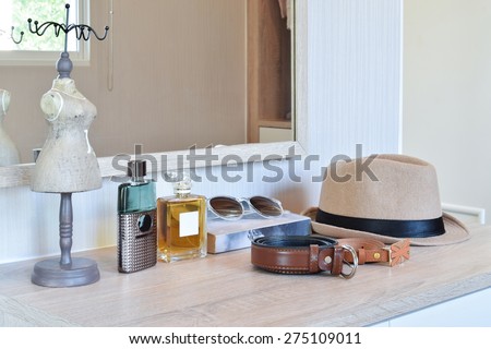 brown hat ,perfume and leather belt on a wooden dressing table
